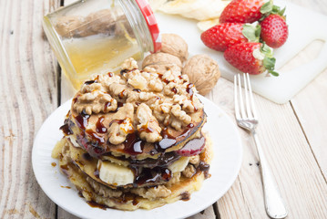 Pancakes with banana , walnut & chocolate on wood background