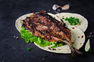 Baked spicy mackerel with flatbread on dark stone backgrond. 