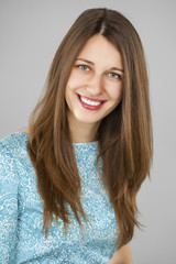 Naklejka premium Portrait of a beautiful young woman in a turquoise dress on a gr