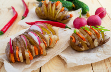 Homemade potatoes baked on a thin stick with bacon and herbs on a wooden background. 