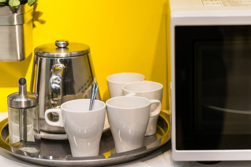 Tea set and microwave against yellow wall
