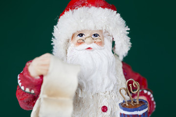 figurine of santa claus with gift list and vase.