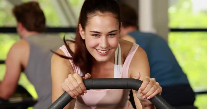 Fit woman doing exercise bike smiling to the camera