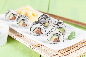 Uramaki sushi with avocado, raw salmon and black sesame