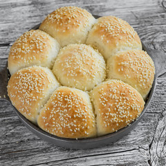 Homemade bread rolls in a vintage pan on wooden background