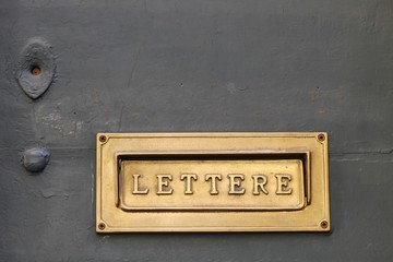 Details of an old Italian letter box on wooden door in Italy