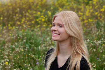 Naklejka premium Happy blonde girl surrounded by flowers