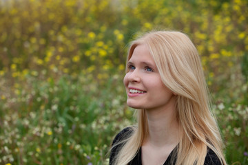 Happy blonde girl surrounded by flowers