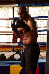 Shirtless Muscular Boxer With Punching Bag In Gym