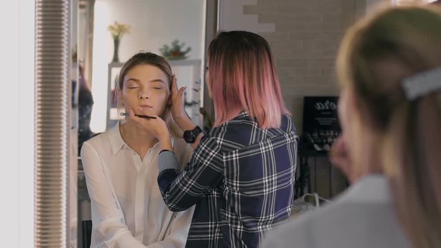 Attractive business woman in a beauty salon. Professional Stylist making make-up day. Nice atmosphere,