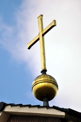 Ein goldenes Kreuz vor blauen Himmel