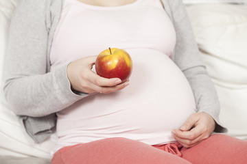 Schwangere hält roten Apfel