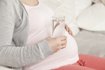 Schwangere hält Wasser in Hand