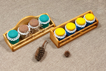 Wooden shelves and multicolored crochet handmade jars of spices