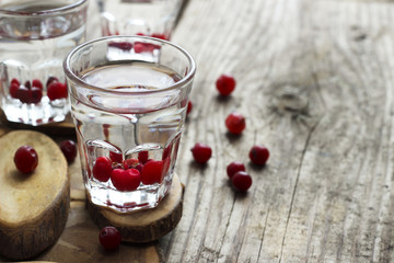 Homemade cranberry vodka, wooden background
