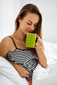 Morning Drink. Closeup Beautiful Happy Smiling Woman Enjoying Cup Of Coffee Or Tea In Morning. Model Drinking Hot Beverage. Girl Lying In Bed, Relaxing At Home. Diet Drinks Concept. Healthy Lifestyle