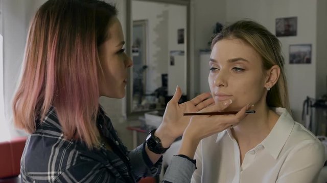 Attractive business woman in a beauty salon. Professional Stylist making make-up day. Nice atmosphere,