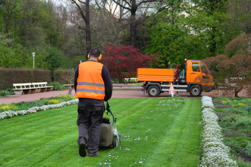Landschaftsgärtner mäht Rasen im Park
