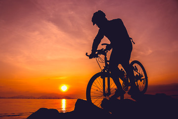 Fototapeta na wymiar Healthy lifestyle. Silhouette of bicyclist riding the bike at seaside.