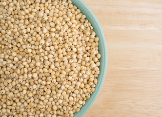 Whole grain sorghum seeds in a bowl on a table.