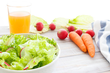 healthy food: light diet salad with fresh lettuce and radish and fresh vegetable juice with carrot on white wooden background