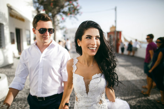 Happy beautiful newlyweds walking on the street