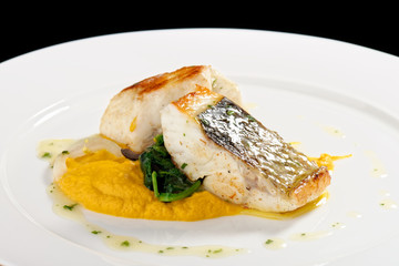 Fine dining Seabass fillets on carrot potato purree and spices