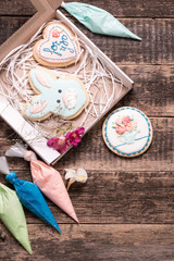 Color icing cookie on wooden background and cornets with glaze for painting