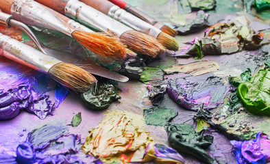 used brushes in an artist's palette of colorful oil paint for dr