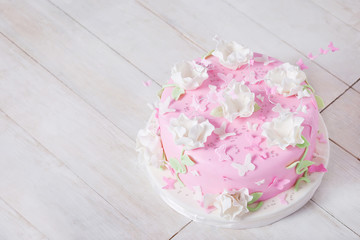 Festive cake with flowers and butterflies on a white wooden tabl