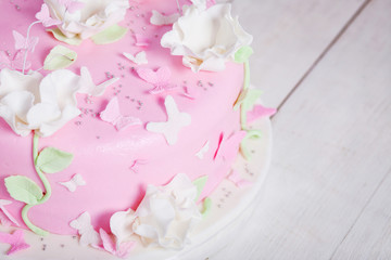 Festive cake with flowers and butterflies on a white wooden tabl