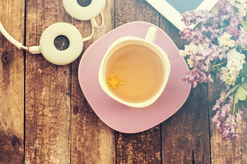 still life with tea cup and the contents of a work space composed. Different objects on wooden table. tablet,phone with headphones and spring flowers