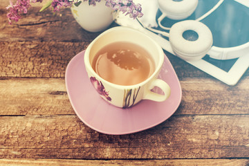 still life with tea cup and the contents of a work space composed. Different objects on wooden table. tablet,phone with headphones and spring flowers