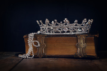 low key image of decorative crown on old book. vintage filtered.