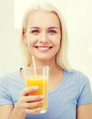 smiling woman drinking orange juice at home