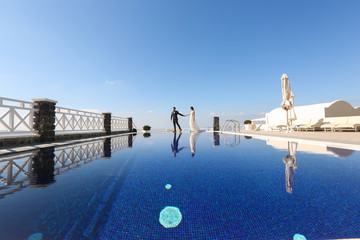 bride and groom walking around a pool