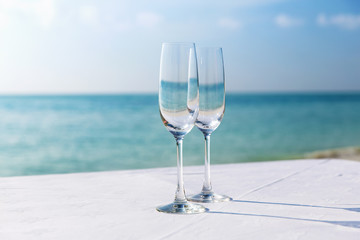  close up of two champagne glasses on beach 