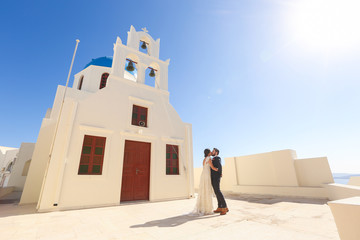 bride and groom posing near a white church
