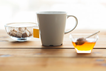 close up tea cup with honey and sugar on table