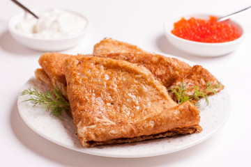 crepes with red caviar and sour cream, isolated on white