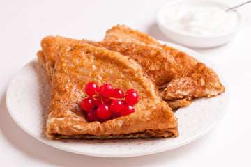 crepes with red currants and sour cream on a plate