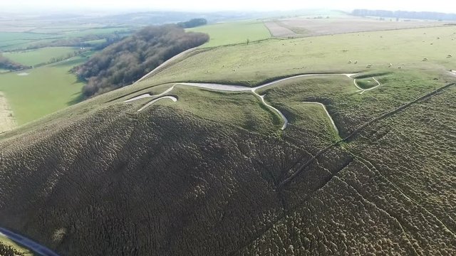 Aerial view looking across a hillside with a large white horse on the side made from chalk 