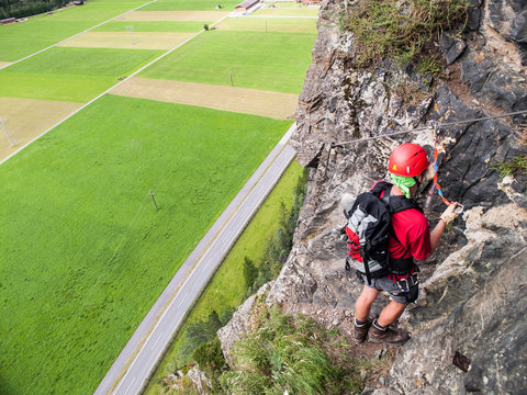 Climber on via ferrata high above road