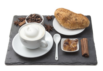 Coffee cup and cake on table. Latte and cappuccino art with milk cream. Hot coffee and bun with cinnamon sticks, coffee beans, and anise star. Sweet food and desert.  Real foods.