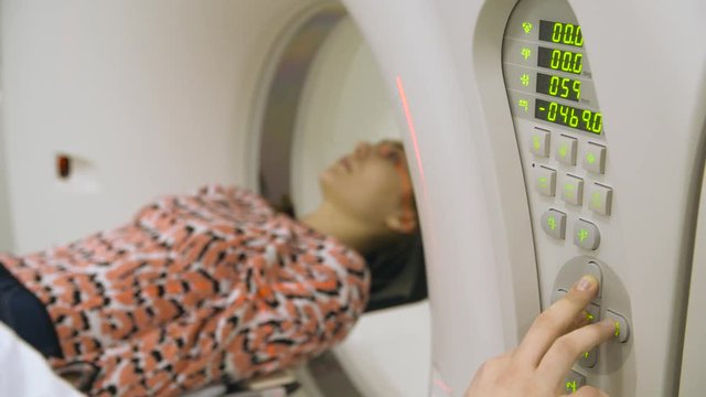 Unrecognizable doctor pushing button on mri machine to move in the patient