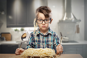 Surprised young boy in glasses with spaghetti