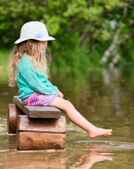 Obraz premium Cute girl sitting on the bank