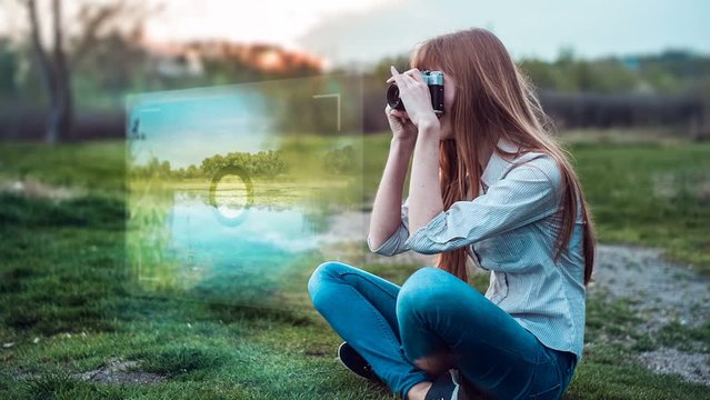 Girl taking photos with old film camera sitting on grass with viewfinder projection hologram.