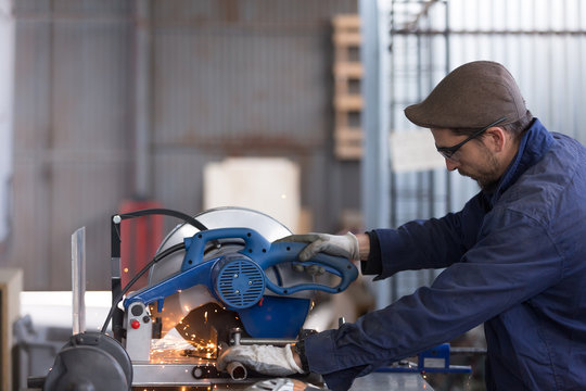 Side view of bearded master working with saw machine
