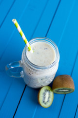 Smoothie with banana, kiwi and milk on blue wooden background, B